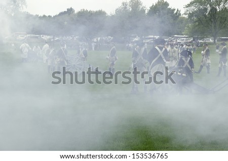WHEATON, ILLINOIS/USA - SEPTEMBER 7: American Revolutionary War (1775-1783) reenactment on September 7, 2013, in Wheaton, IL. Smoke from cannon obscures actor-soldiers in mock battle near parking lot.