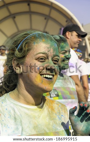 KALAMAZOO, MICHIGAN, USA - April 12, 2014: A young woman runner beams after a dousing of colored powder following a 5K \