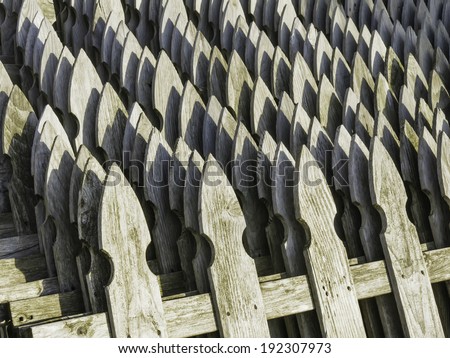 Pattern of weathered wooden fence posts, shaped like arrowheads, near sunset