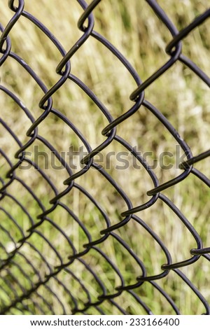Receding pattern of chain-link fence (shallow depth of field), for themes of dependability, safety, protection, and transparency