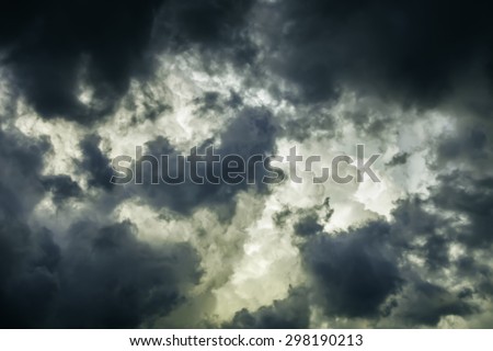 Storm clouds in summer: Ragged wind-driven dark clouds move in quickly to obscure large white billows before sunset, for meteorological themes of instability and rapid change