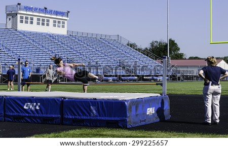 PARK RIDGE, ILLINOIS, USA - July 23, 2015: A woman jumps over the high bar during a track and field competition of the Six-County Senior Games on a summer morning in suburban Chicago.