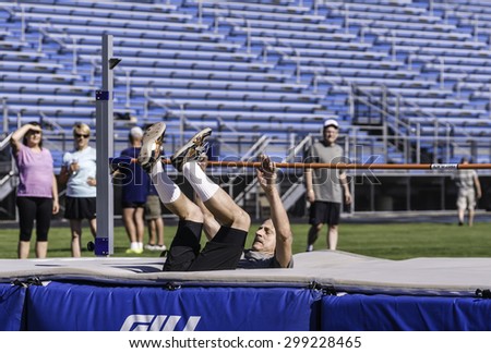 PARK RIDGE, ILLINOIS, USA - July 23, 2015: A senior high jumper lands safely  during a track and field event in the Six-County Senior Games, held by the Illinois Park and Recreation Association.