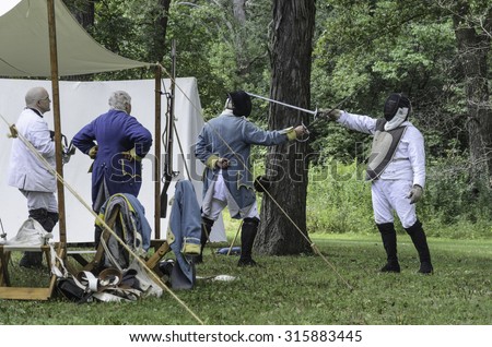 WHEATON, ILLINOIS/USA - SEPTEMBER 12, 2015: Two male actors rehearse a sword fight in a military camp before mock battle at a reenactment of the American Revolutionary War (1775-1783).