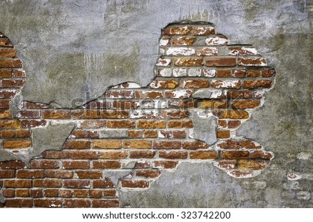 Vintage architectural grunge: Old brick exposed beneath thin concrete fallen off face of exterior wall