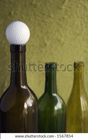 Golf ball on mouth of empty wine bottle (focus on golf ball)