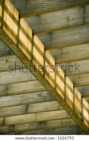 Wooden beams supported by cross beam with morning shadows