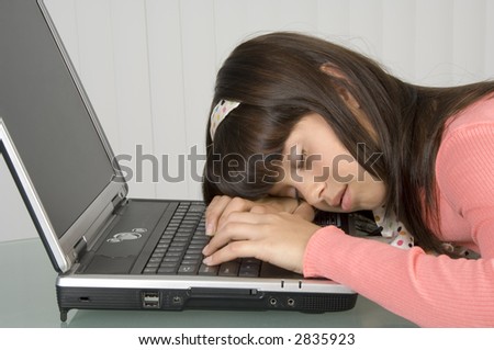 Girl in pink asleep, head and hands resting on computer keyboard