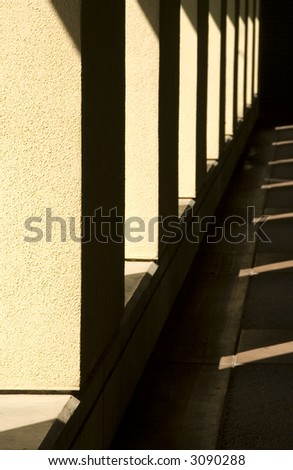Passageway with sunlight and shadow outside building on college campus in southern California (focus on nearest stucco column)
