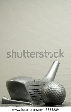 Golf trophy - silver-coated driver head, tee, and ball - with beige paper background inside trophy case
