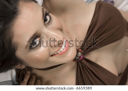 Close-up of pretty young Caucasian brunette with dark eyes looking at you, view from above
