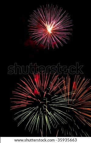 Pinkish burst of fireworks with white-hot core above embers of two other explosions