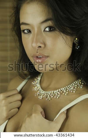 Portrait of beautiful young Asian-American woman, thumbs under the straps of her white brassiere