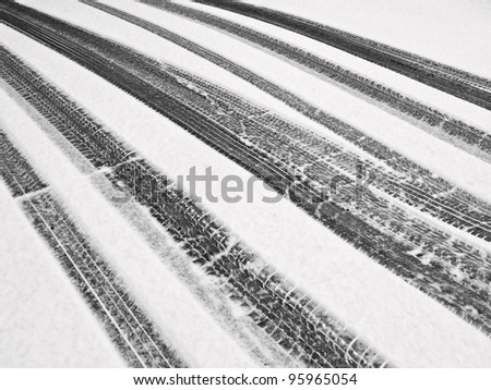Winter at a glance, in black and white: Recent tire tracks through snow on ramp to garage