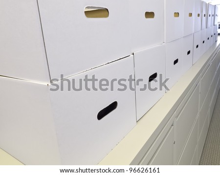 Neatness at the office: White cardboard storage boxes stacked along top of corridor cabinet