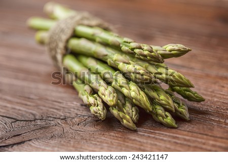 bunch of asparagus stems on brown wooden table. One of 5 greens a day