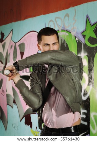 young man chopping with baseball bat against graffiti wall