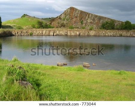 Lake and rock face under a stormy sky, by Hadrian\'s Wall in Northumberland UK,