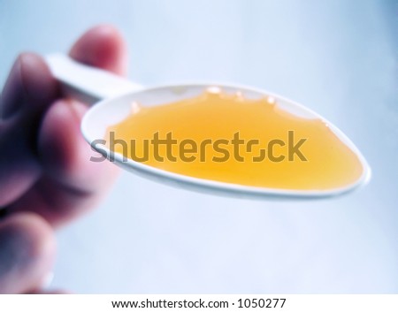 A spoonful of bright orange medicine on a white spoon, bold close-up