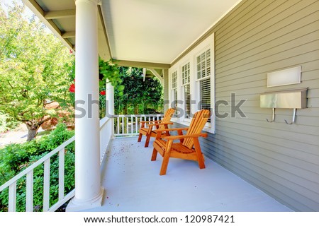 Front porch with chairs and columns of old craftsman style home.