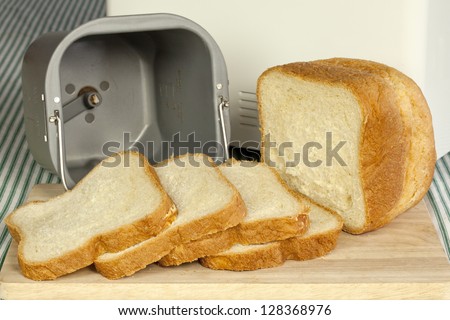 Bread machine with pan and fresh white bread at home.