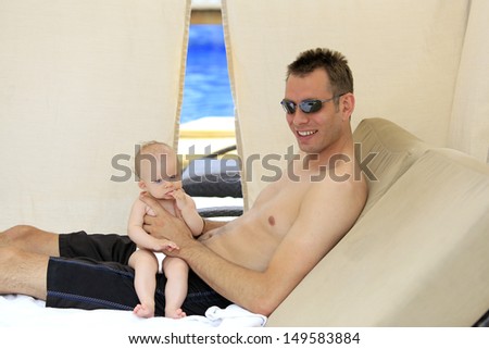 Father and baby are playing  on vacation in the pool day bed.
