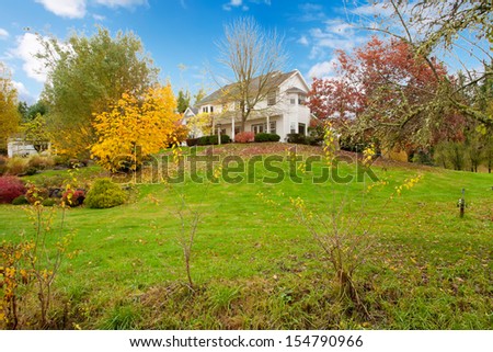 Northwest horse ranch white house with fall changing leaves and white fence.