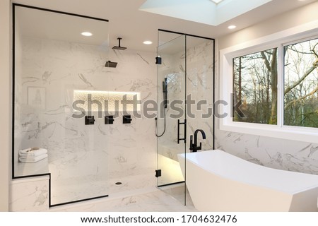 Detailes of the larhe walk in shower with white marble and mosaic, light. Three handles, shower head in dark brass.and free standing modern tub.