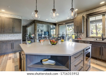 Absolutly stunning kitchen interior with grey tone of brown muted natural tones with light hardwood and rustic modern island with colorful plates.