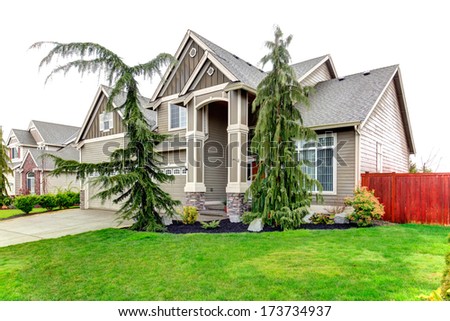 BIg siding house with porch columns stoned at base, tile roof and beautiful flower bed and trim