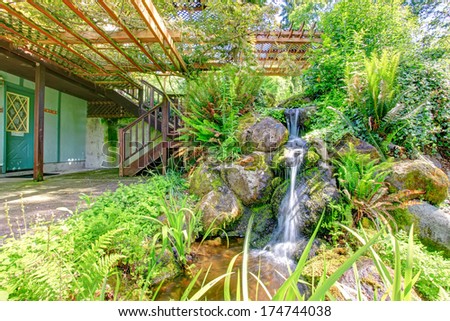 Backyard farm house deck open to beautifully designed pond with stones and waterfall.