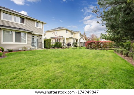 Backyard area with flowerbed, large green trimmed spot and trimmed hedges