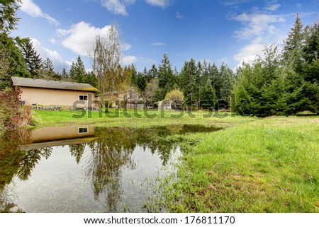 Green backyard with shed, forest and small man made lake
