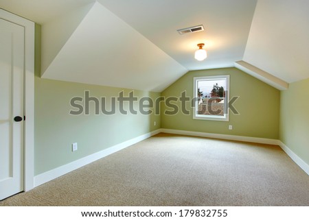 Bright empty room with one window, beige carpet floor, green walls and white vaulted ceiling