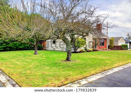View of the house with green lawn and trees from a drive way. Simple yet beautiful curb appeal