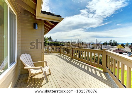 Wooden walkout deck with a chair overlooking road and neighborhood
