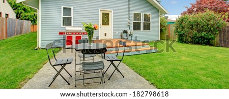 View of siding house with fenced backyard, View of green lawn, small concrete floor patio area with table set