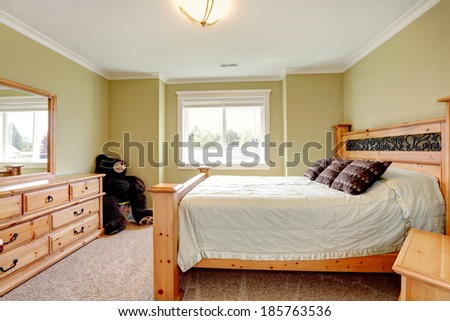 Light tones bedroom with lime walls and beige carpet floor. Furnished with queen size bed, dresser with mirror.