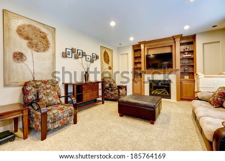Furnished luxury living room with leather ottoman. View of fireplace with tv and built-in cabinet