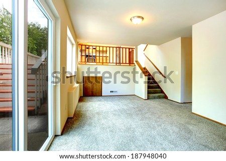 Empty ivory room with walkout deck. View of staircase to kitchen room