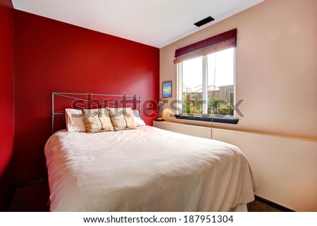 Small bedroom with red and cream wall. Iron frame bed with tropical theme bedding