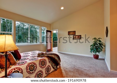 High ceiling master bedroom with walkout deck.  Decorated with wall pictures and fake tree