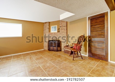 Empty living room with tile floor. View of corner with fireplace decorated with wicker basket and rustic chair