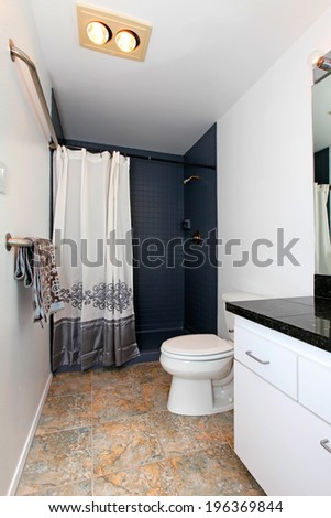 White bathroom with tile floor and tile wall trim. Decorated with towels and curtain