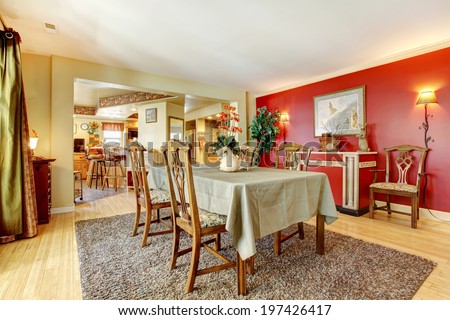 Dining room with red and ivory walls, hardwood floor and brown carpet. Furnished with antique dining table set and cabinet