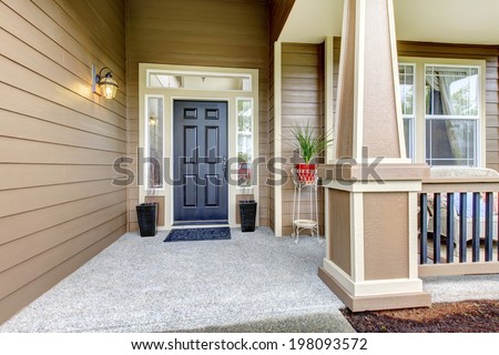 Entrance porch with black door, column and railings. Porch decorated with flower pots