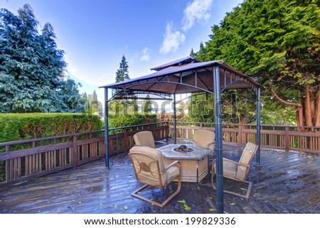 Wooden deck with railings and gazebo with fire pit and chairs