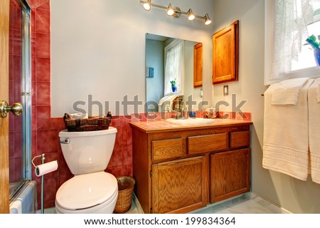 Bathroom with red tile wall trim, old wooden cabinet and white toilet