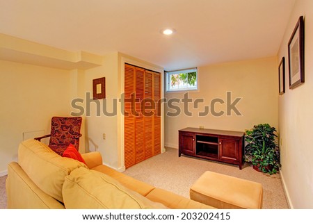 Soft ivory room with sofa, chair and cabinet. Room decorated with fake tree