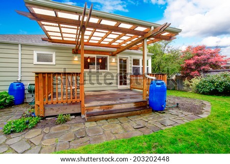 Small house with backyard walkout deck. View of wooden deck with railings and rock tile walkway